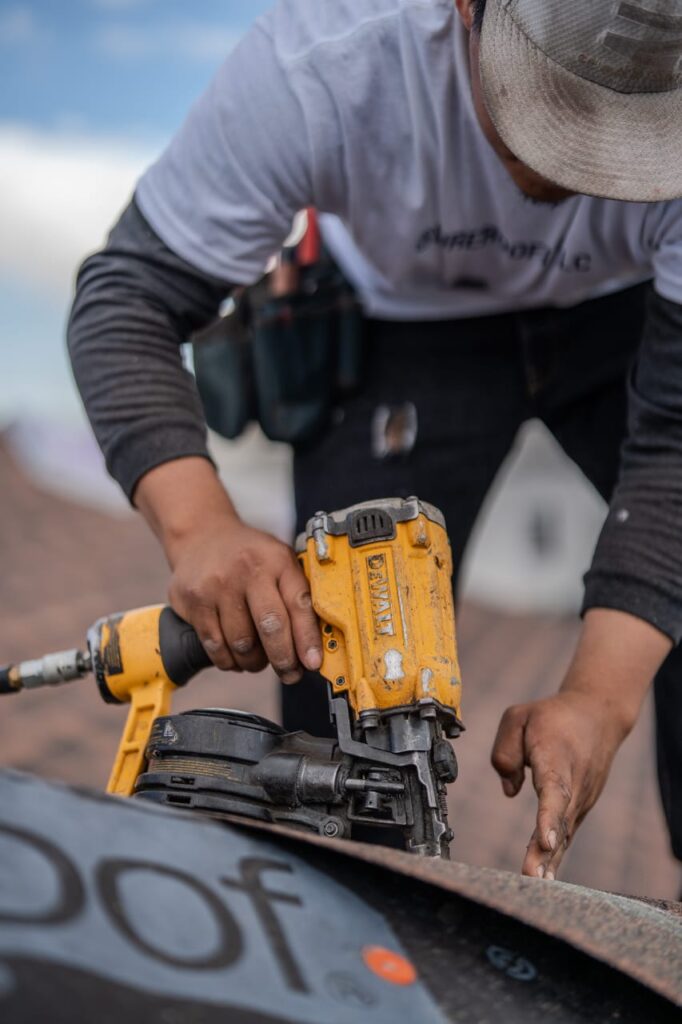Professional roofer using pneumatic nail gun for roof installation in Victorville CA