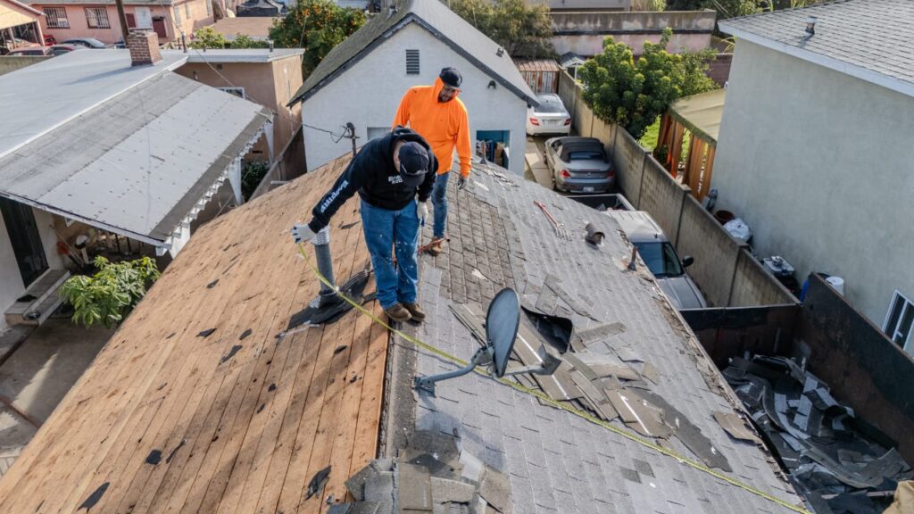Professional roofing contractor installing asphalt shingles on residential home in Victorville California